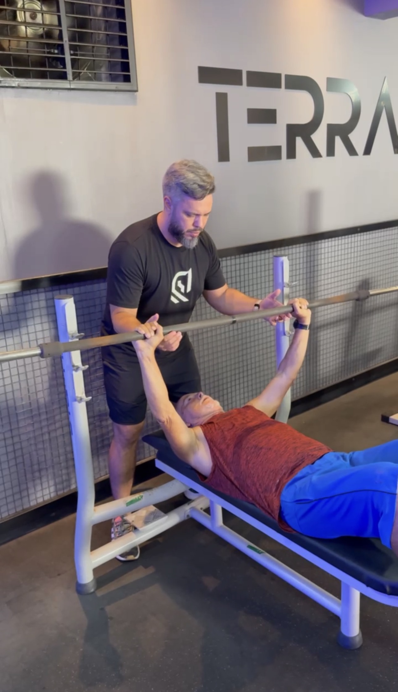 Marcus Terra atento à execução de um exercício com barra durante o atendimento individual